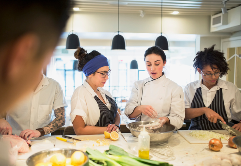 Three women standing at a kitchen counter preparing food together
