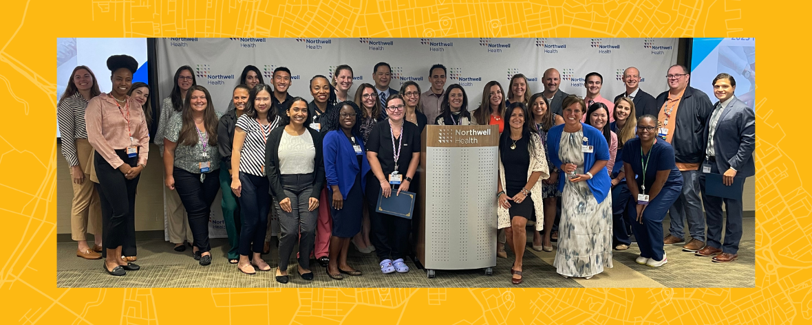 A large group of Northwell team members standing together in front of a large Northwel Health backdrop.